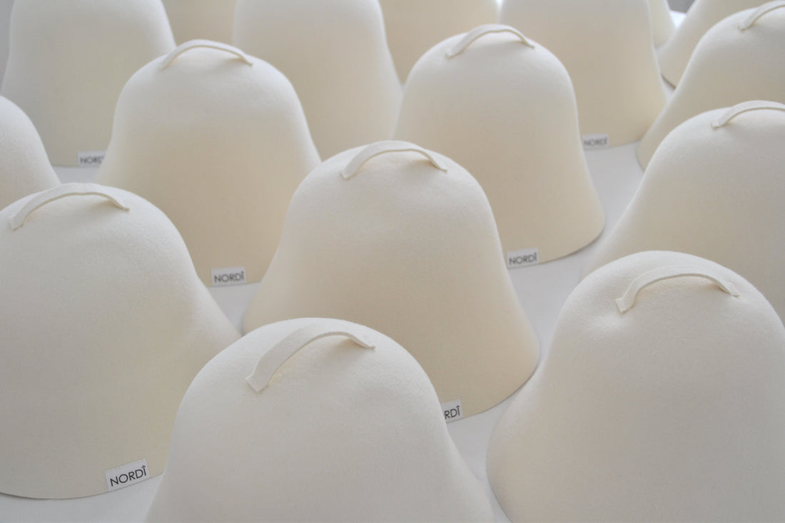 Rows of handcrafted NORDI sauna hats in undyed white, made from premium 100% Rambouillet wool to provide superior heat insulation.